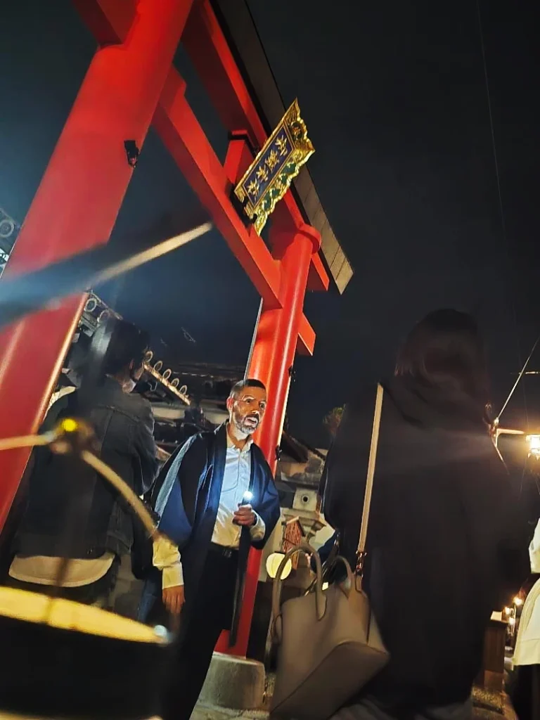 Guide of the Nara Ghost Tour telling a story in front of the entrance of a shrine